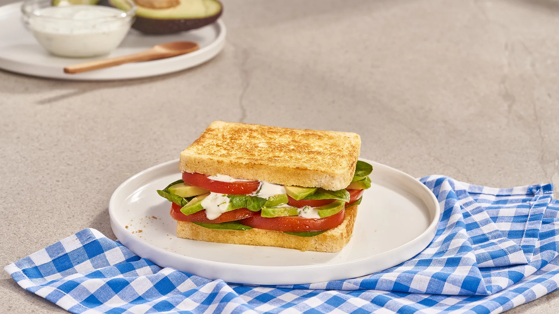 Sanduíche com abacate, tomate, folhas de espinafres e molho de iogurte caseiro