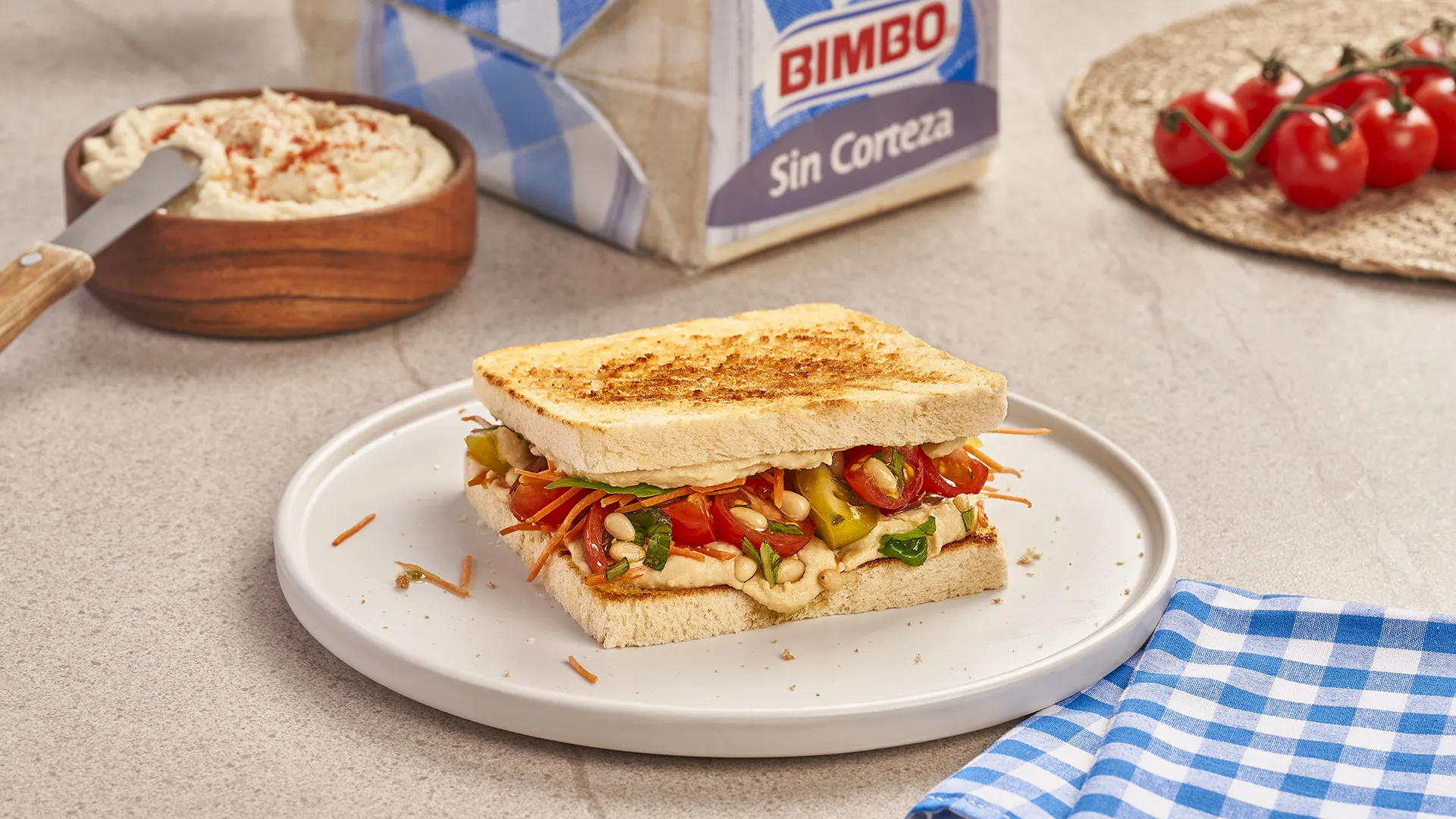 Sanduíche de húmus, cenoura ralada e tomate com molho de manjericão fresco e pinhões
