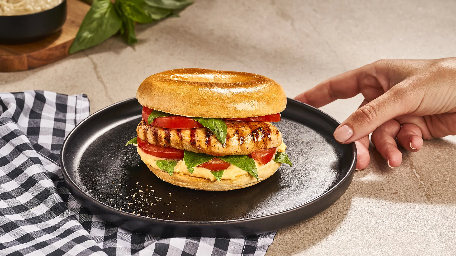 Bagel com frango grelhado, húmus, tomate e manjericão