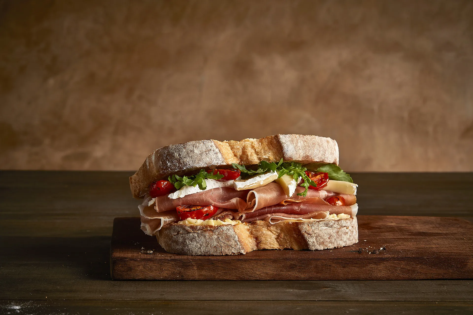 Sanduíche de presunto serrano, queijo brie, tomate, rúcula e mostarda dijon