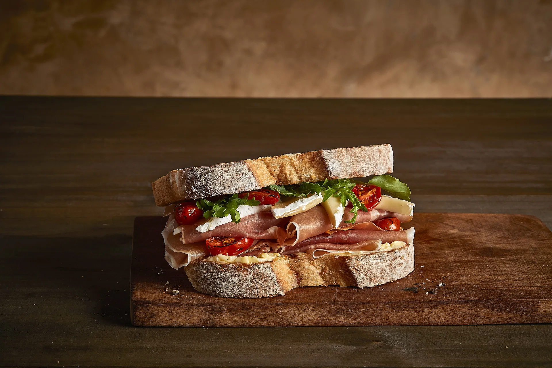 Sanduíche de presunto serrano, queijo brie, tomate, rúcula e mostarda dijon