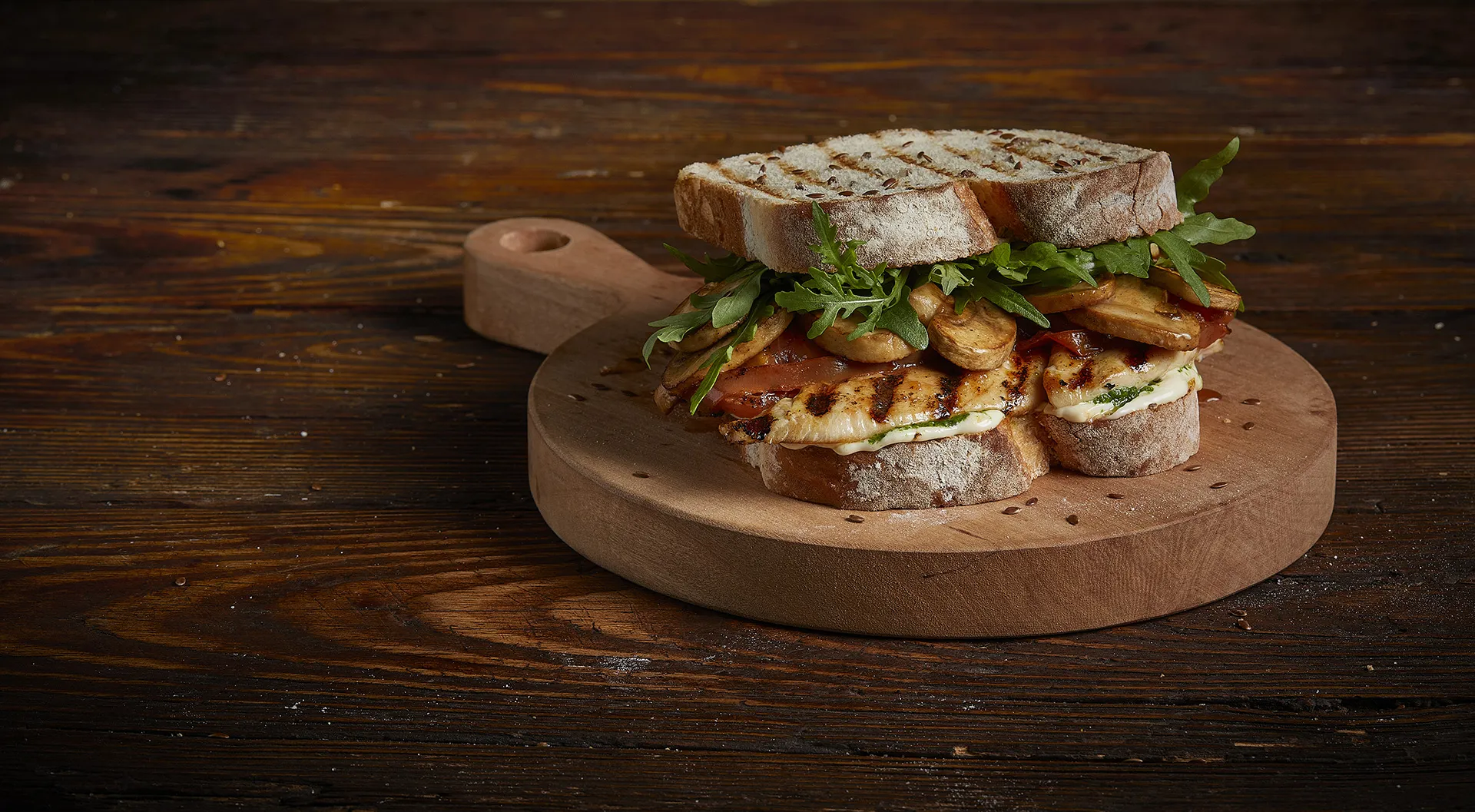 Sanduíche de frango grelhado com tomates secos, cogumelos, rúcula e molho de alho